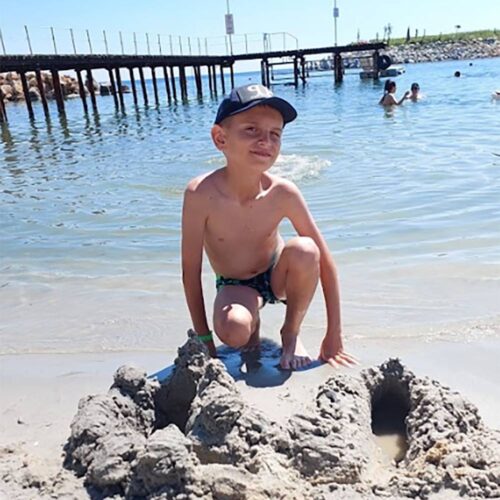 A child at the beach playing with sand.