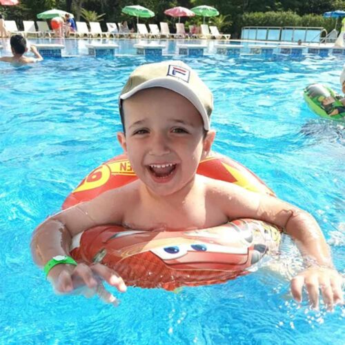 A young child swimming with a hat on.