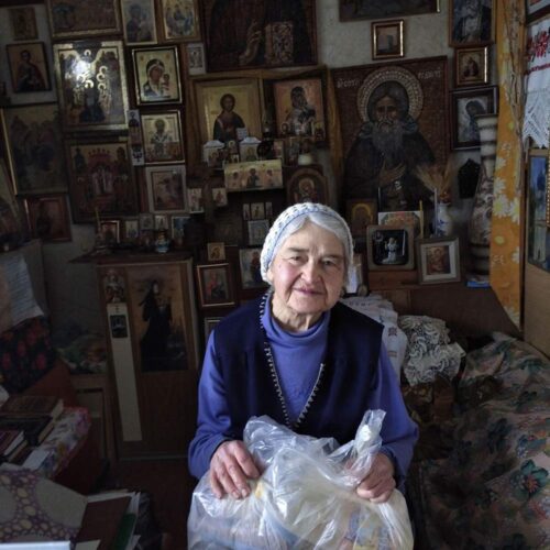 An elderly person sitting in a chair with a plastic bag.