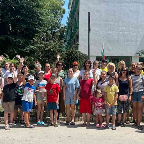 A group of adults and children waving and smiling.