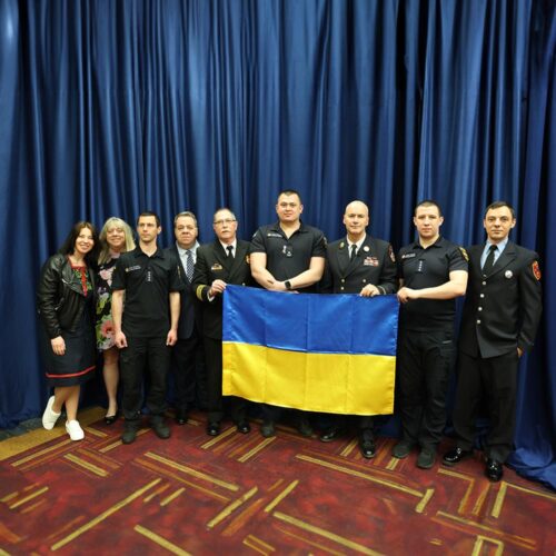 A group of people smiling and holding a flag.