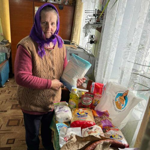 A person holding a bag of flour next to food supplies,