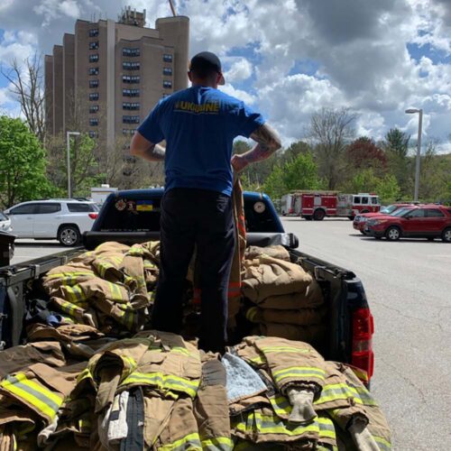 A person in a pickup truck filled with firefighter uniforms.