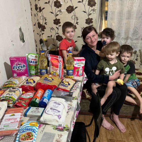 A woman with her young children with a table of food.