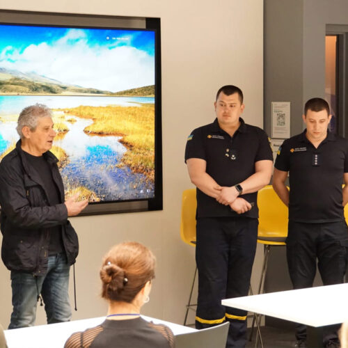 A man giving a speech introduction for two firefighters.