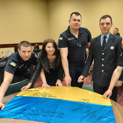 A group of firefighters smiling for a signed flag.