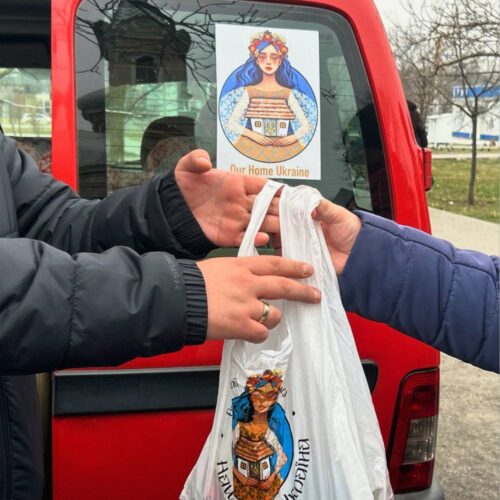 Two hands exchanging a plastic bag with food inside.