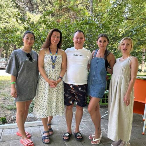 A group of people smiling with a tree behind them.