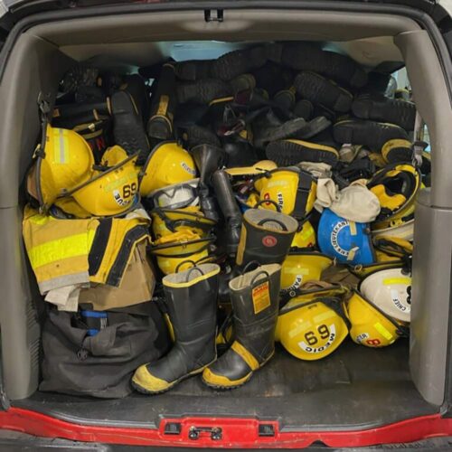 A car trunk filled with firefighter gear.