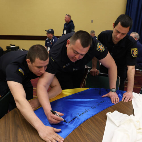 Three firefighters signing a flag.