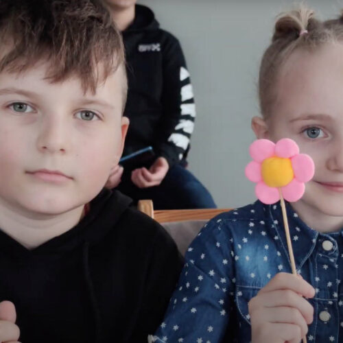 Two young children holding a flower craft.