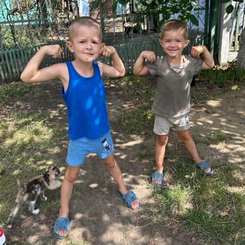 Two young children flexing their arms.