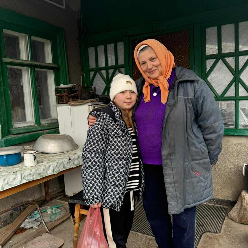 Two people smiling next to green windows.